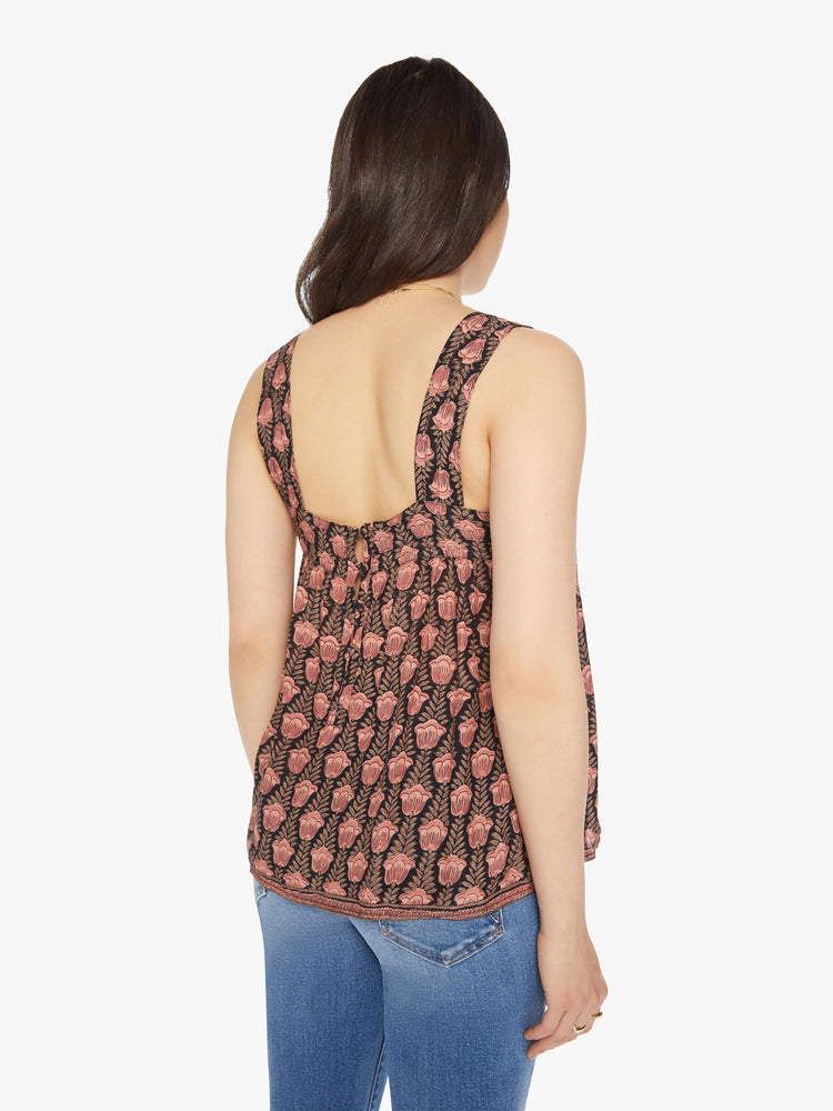 Back view of a woman top designed in brown with a baby pink tulip print, and features detailed straps and buttons in the back.