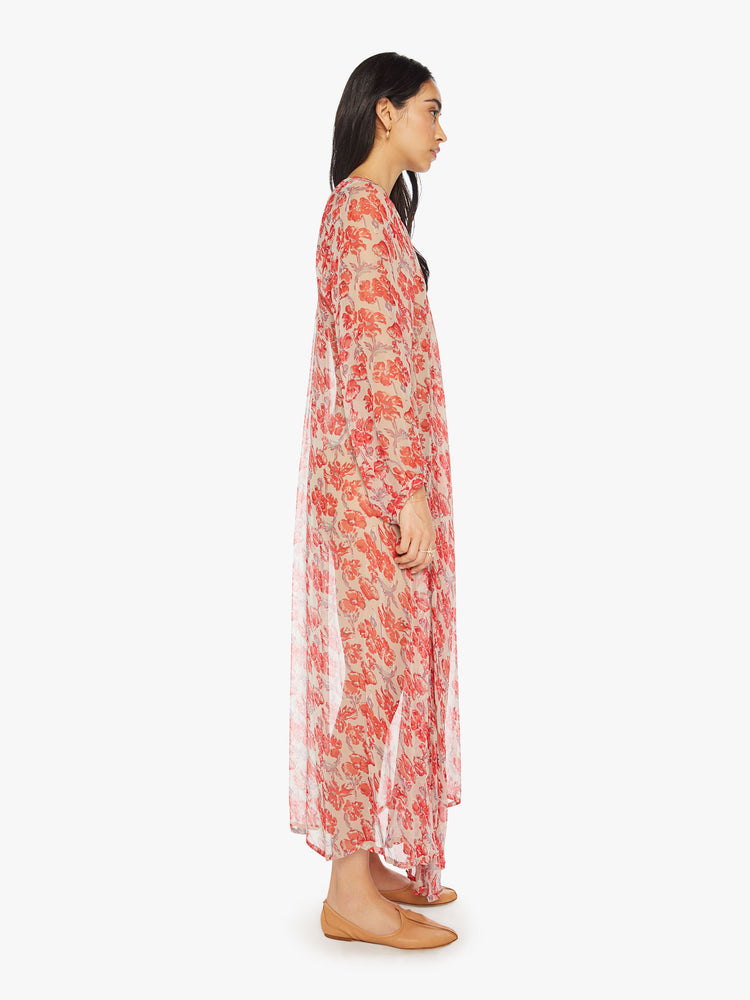 Side view of a woman sheer nude and red watercolor floral print maxi dress with designed with voluminous sleeves and has an A-line cut.