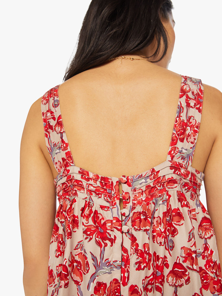 Close up back view of a woman top in nude with a red watercolor floral print, and features detailed straps and buttons in the back.