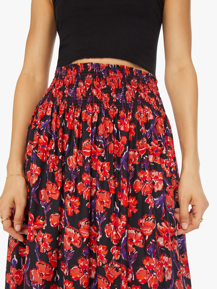 Close up waist view of a woman black/red watercolor floral print with a smocked waistband and a loose, flowy fit.