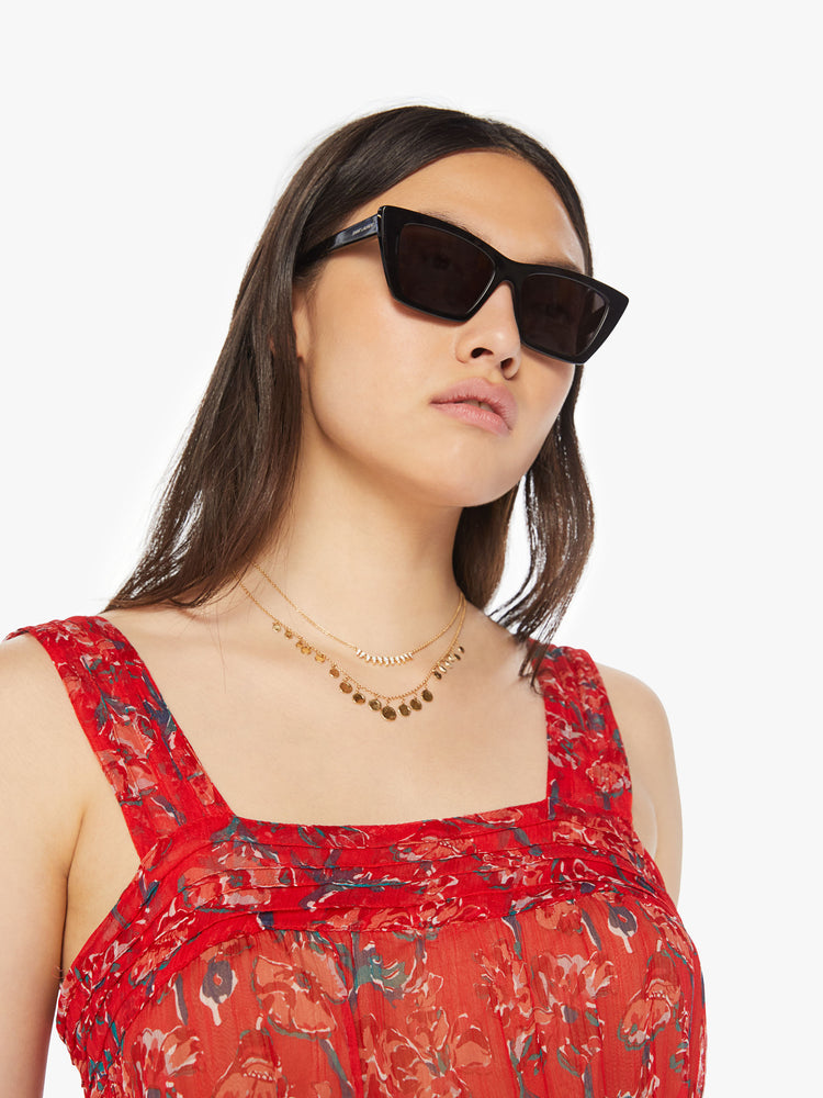 Close up view of a woman red maxi dress with colorful print with a square neck, detailed straps, optional waist sash and an ankle-grazing hem.