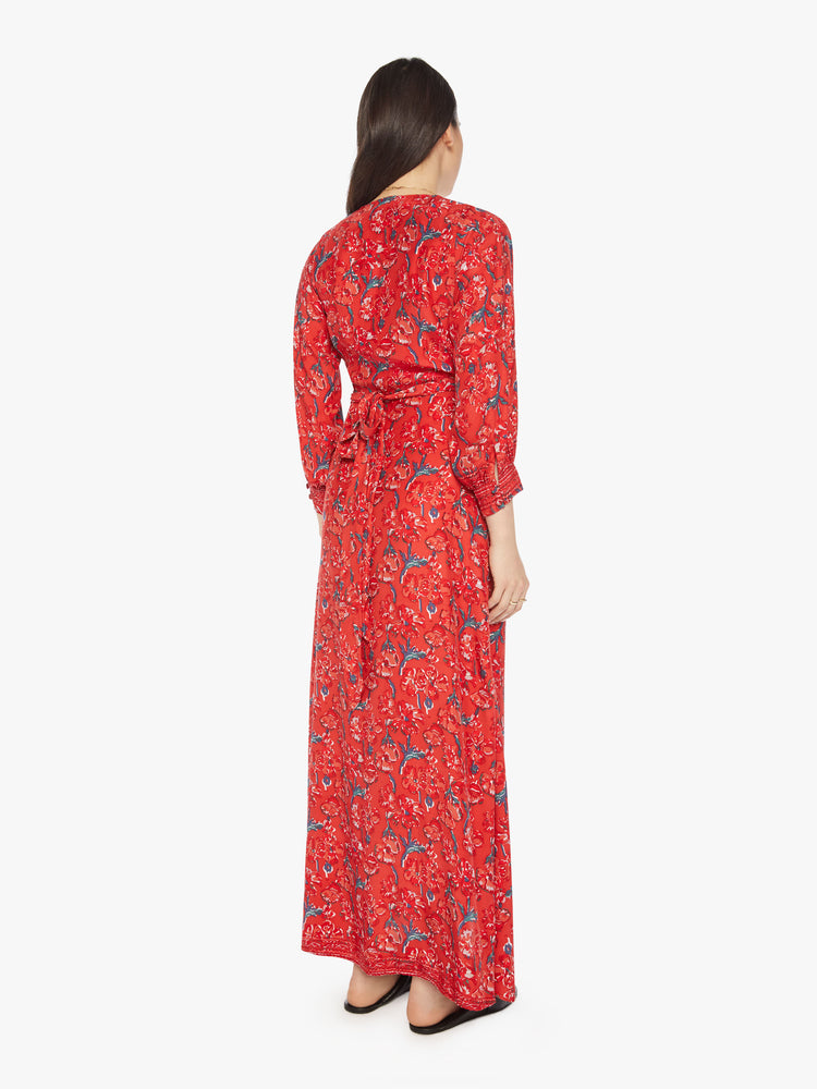 Back view of a woman in a red dress with a colorful floral print, and features a V-neck, tied waist and long maxi skirt with a loose, flowy fit.