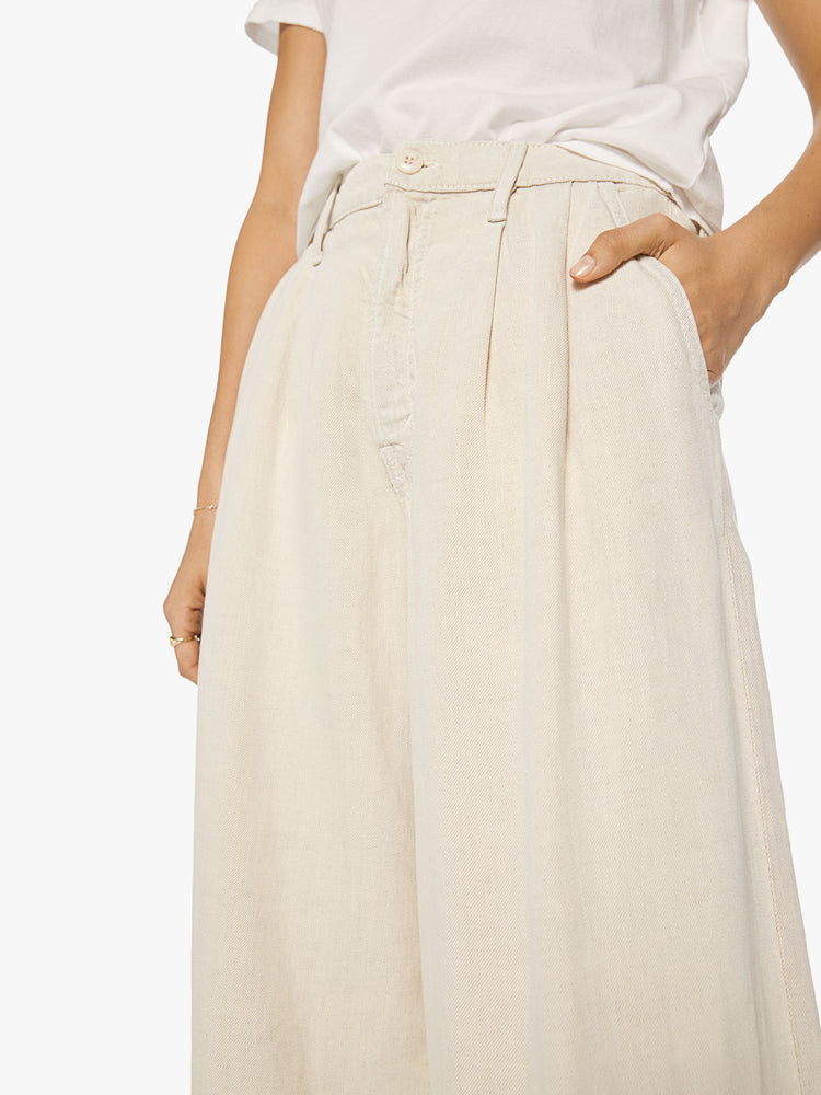 Close up view of a woman Super high-waisted wide-leg pants with a long 34-inch inseam that puddles at the hem in a creamy hue.