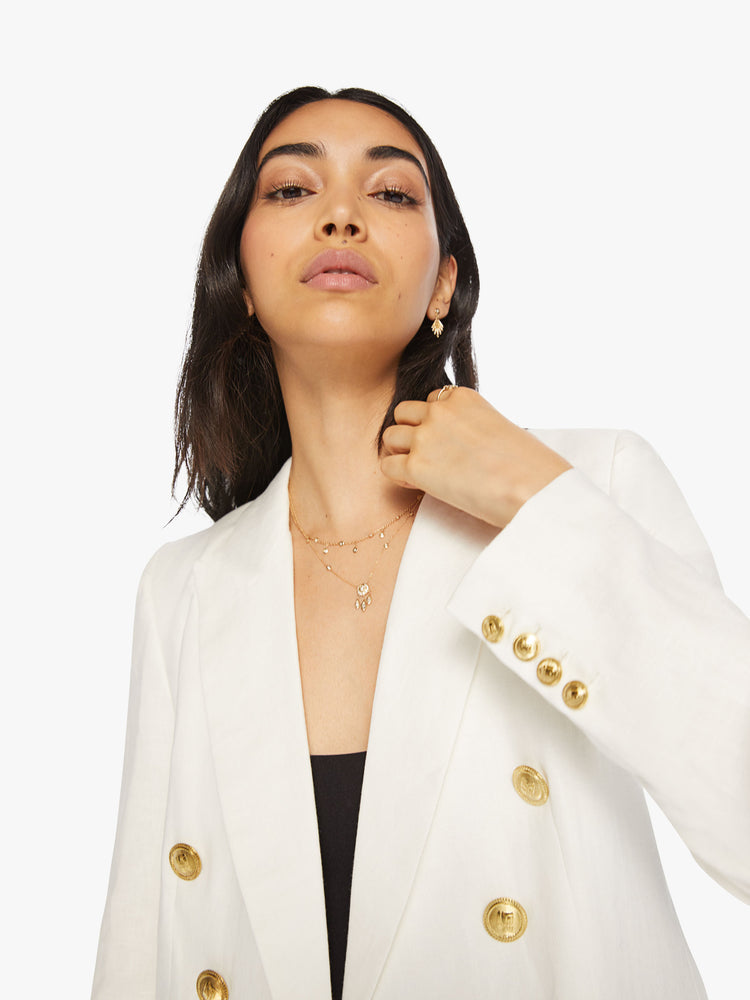 Close up view of woman white v-neck blazer with an extra-wide collar, padded shoulders and a button closure.