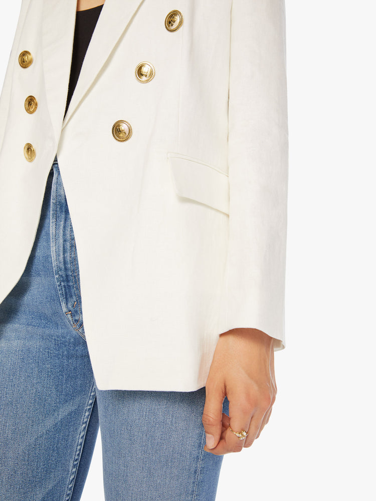 Button close up view of woman white v-neck blazer with an extra-wide collar, padded shoulders and a button closure.