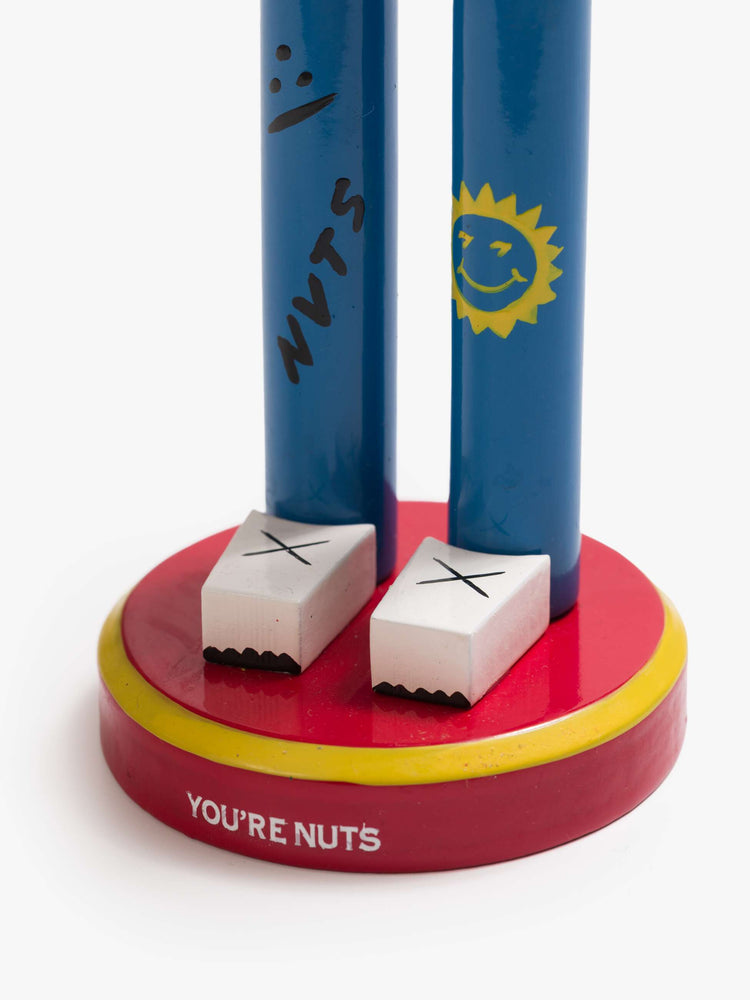 Feet close up of a traditional nutcracker with a headband, embroidered scarf and doodled jeans.