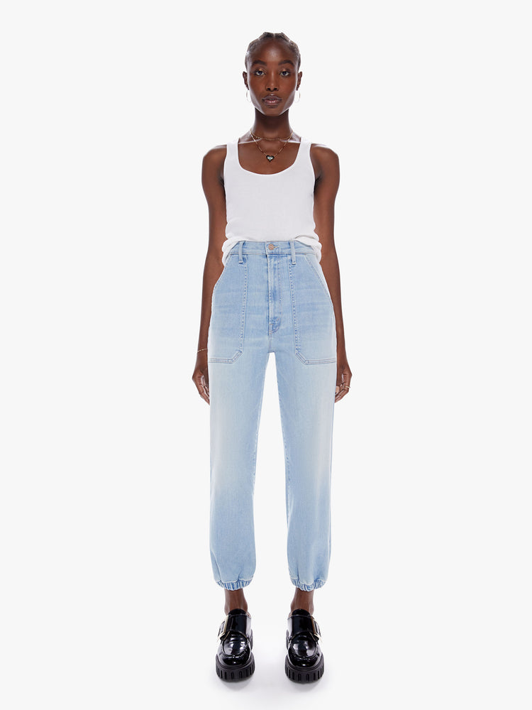 Front view of a woman in a high waisted straight leg jean with elastic cuffs at the ankle and oversized patch pockets in a light blue wash with fading and whiskering cut from denim with a touch of stretch