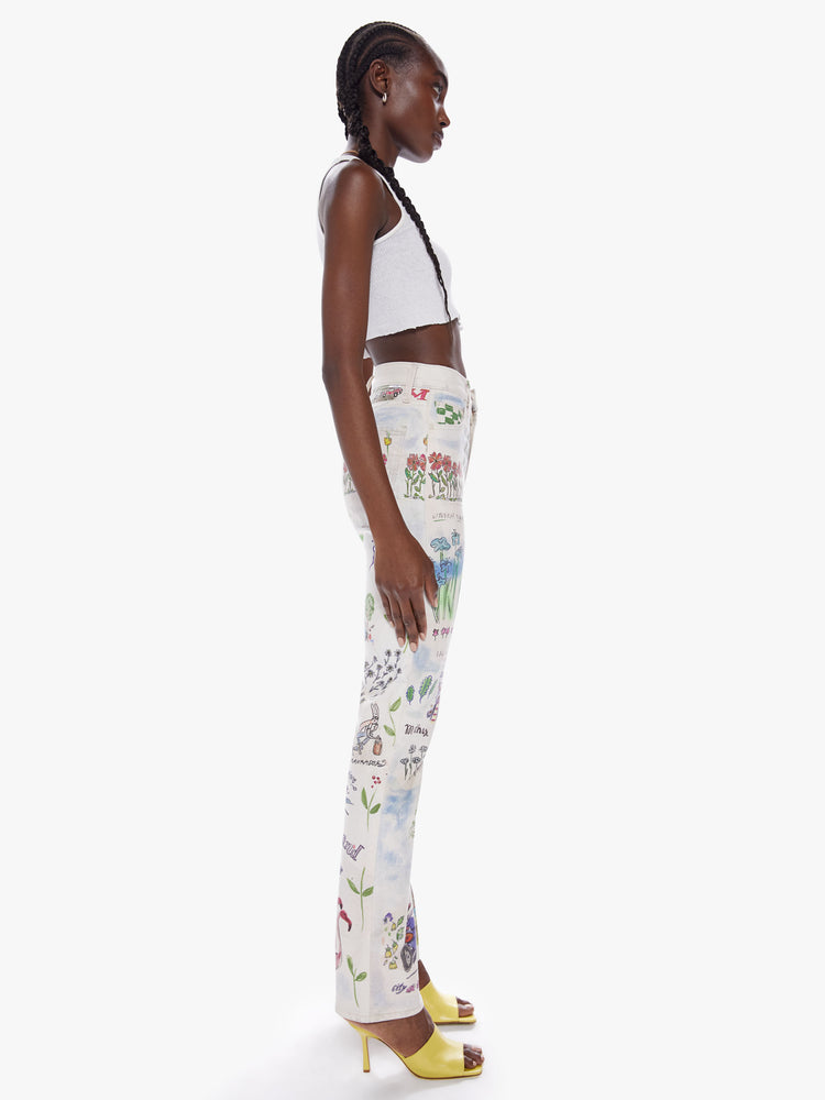 Side view of a woman high-waisted straight leg has a 31-inch inseam and a clean hem in an off-white hue with colorful, storybook-inspired graphic illustrations.