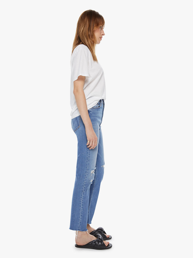 Side view of a womens medium blue wash jean featuring a high rise and a distressed straight leg.