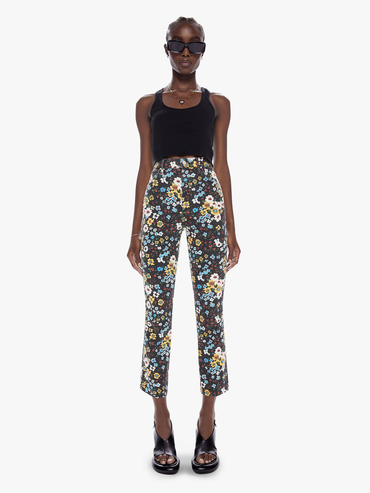 Front full body view of a woman in a high rise flare with a narrow leg, ankle length inseam, and a clean hem made from cotton with a touch of stretch, pushing daises is a high contrast floral print in black, blue, yellow, red, and white