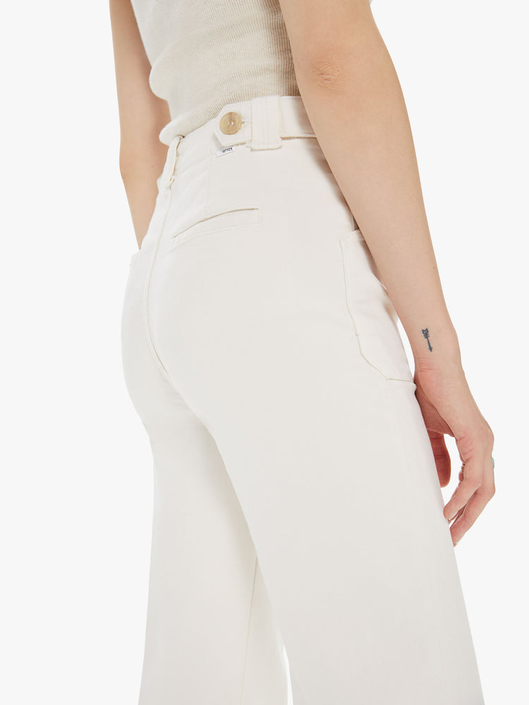 Side close up view of a womens off white pant, featuring a high rise, a wide relaxed leg, and patch pockets.