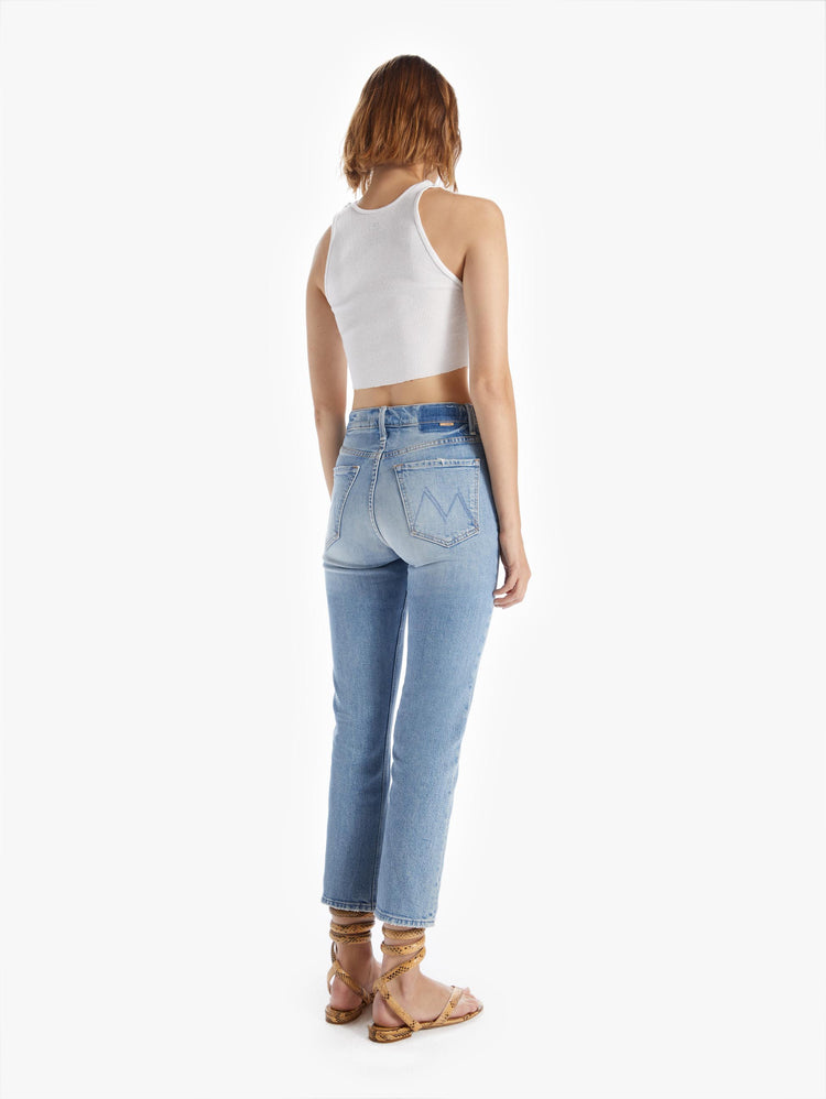 Back view of a woman in an ultra high waisted straight leg with a button fly and clean ankle length inseam cut from superior denim in a light blue wash with whiskering and fading