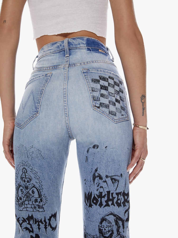 Back close up view of a woman in an ultra high waisted straight leg with a button fly and a clean ankle length inseam cut from semi rigid superior denim in a light blue wash with whiskering, fading and angsty graphic doodles down the legs