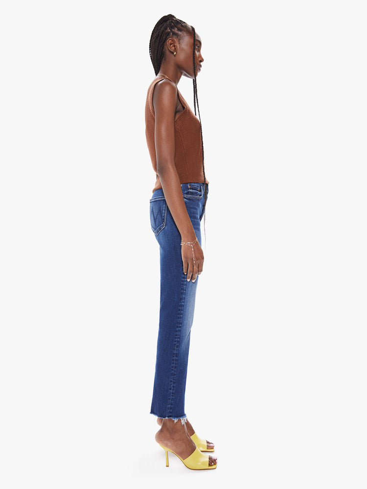 Side view of a women's deep blue straight leg ankle jean with fading