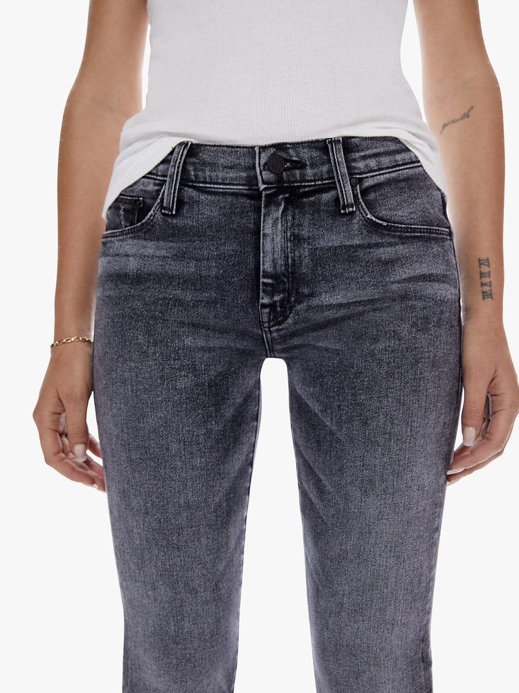 Waist close up view of a woman in a super low rise flare with a long 34 inch inseam and a clean hem cut from soft stretch denim, in a black mineral wash with a high contrast fading throughout