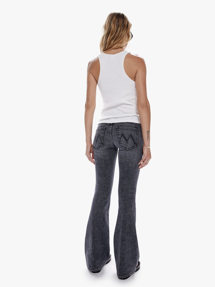 Back view of a woman in a super low rise flare with a long 34 inch inseam and a clean hem cut from soft stretch denim, in a black mineral wash with a high contrast fading throughout