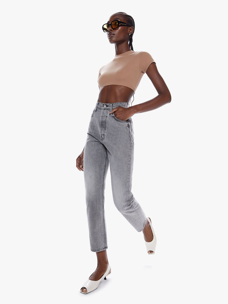 In motion side full body view of a woman in straight leg jean from snacks mothers homage to throwback styles of the 80s and 90s, the super high waisted jean feature a narrow straight leg with a clean ankle length inseam in a washed grey hue