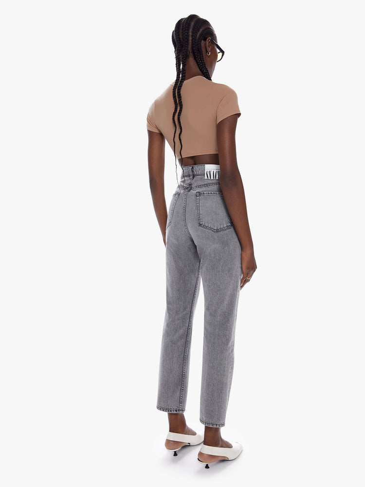 Back full body view of a woman in straight leg jean from snacks mothers homage to throwback styles of the 80s and 90s, the super high waisted jean feature a narrow straight leg with a clean ankle length inseam in a washed grey hue