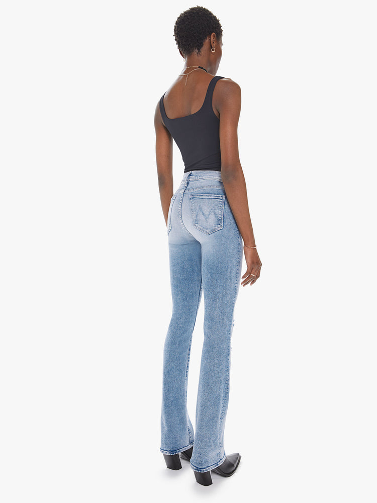 Back view of a womens light blue wash jean featuring a high rise, flare leg, and distressed details at the knees.