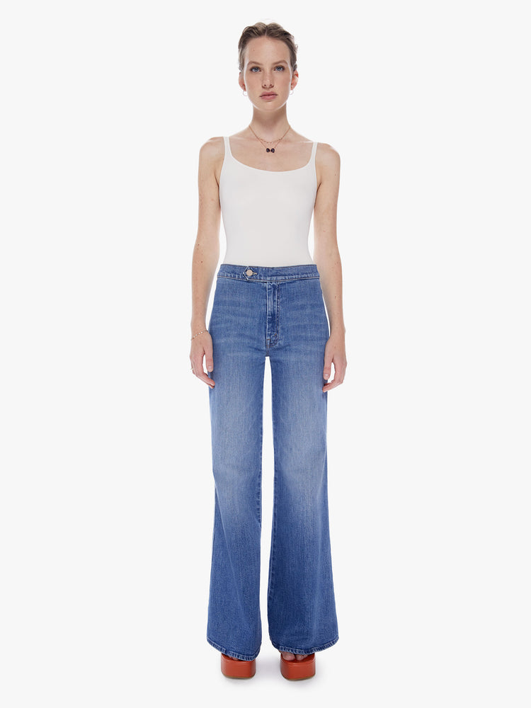 Front view of a woman  70s-inspired wide-leg jeans with a high rise, long inseam, waistband tab and a clean hem in a mid blue wash.