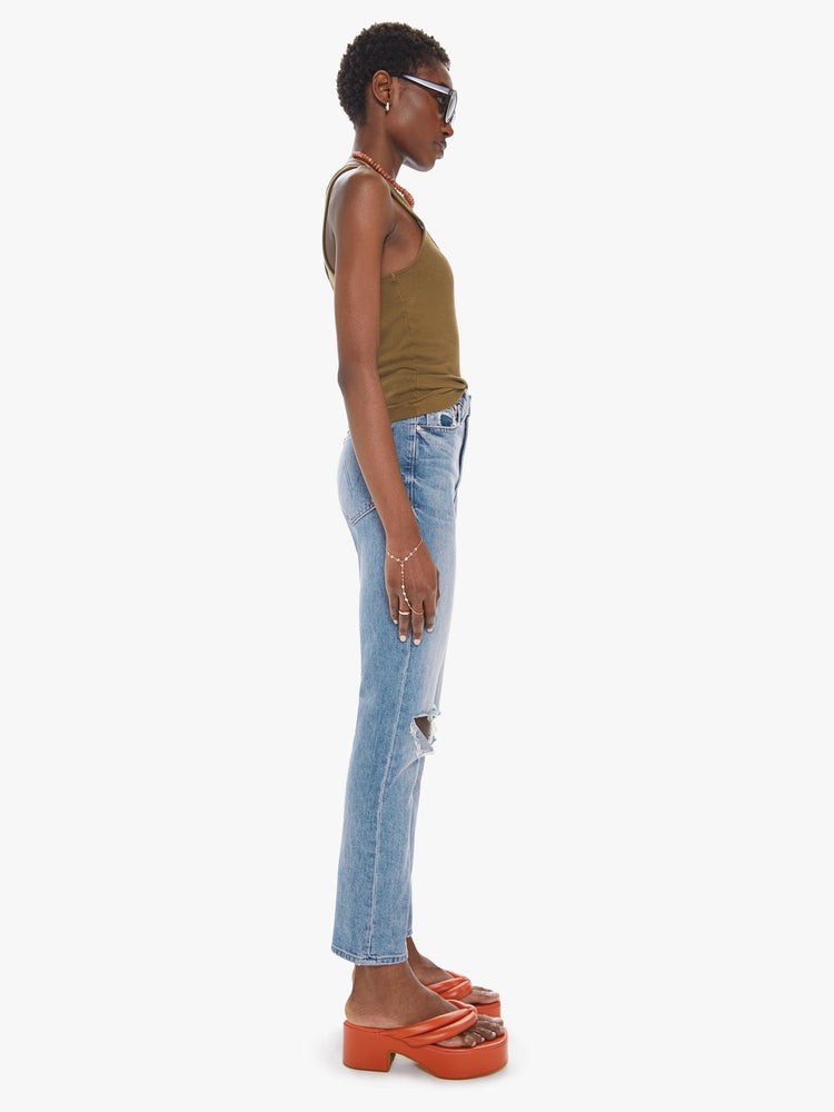 Side view of a womens medium blue wash jean featuring a high rise, straight leg, and distressed details at the knees.