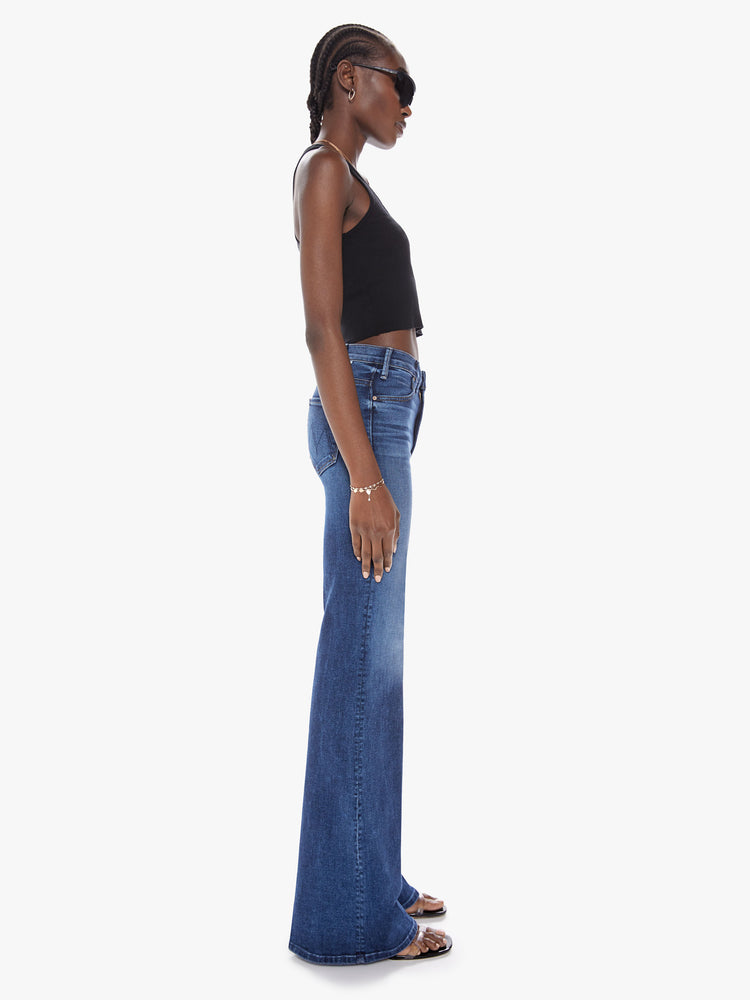 Side view of a womens wide leg dark blue wash jean with a high rise, clean hem and fading at the knees.