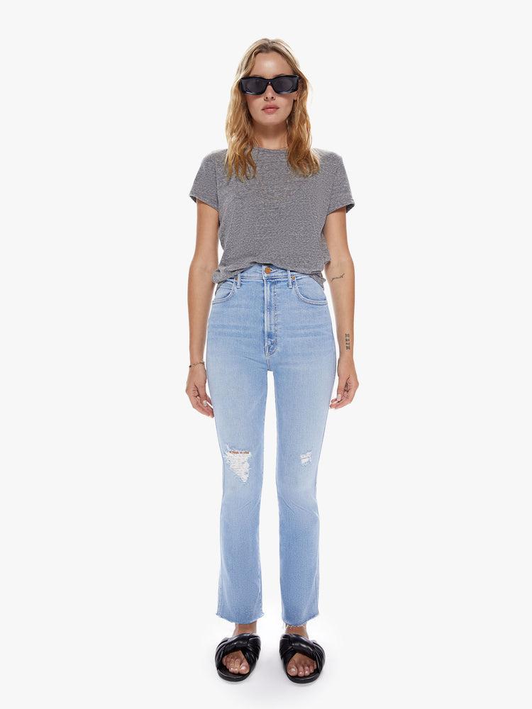 Front view of a womens light blue wash jean with a high rise, frayed hem and distressed knees. 