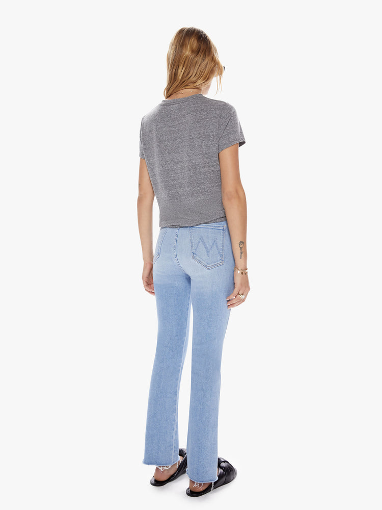 Back view of a womens light blue wash jean with a high rise, frayed hem and distressed knees.
