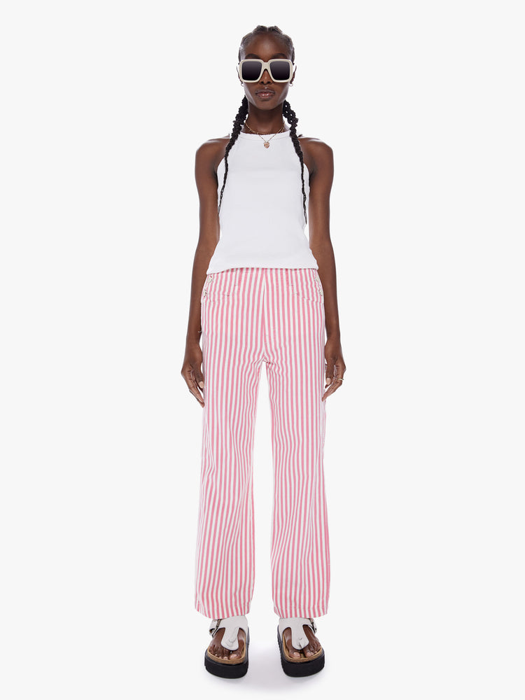 Front view of a woman High-waisted wide-leg pants with buttons at the hips, a hammer loop, a cargo pocket and low-set back pockets in a pink railroad stripe pattern with white buttons.