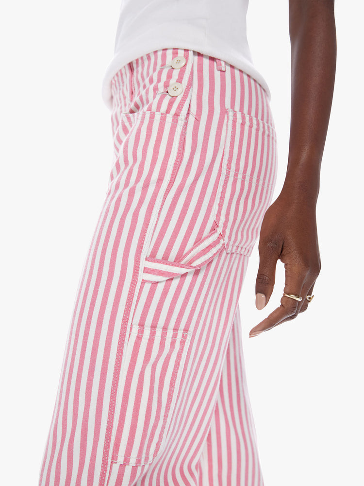 Close up waist view of a woman High-waisted wide-leg pants with buttons at the hips, a hammer loop, a cargo pocket and low-set back pockets in a pink railroad stripe pattern with white buttons.