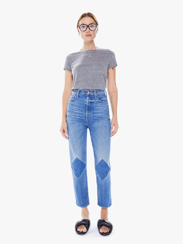 Front view of woman Ultra high-rise jeans with a straight, narrow leg and a cropped inseam in mid-blue wash with dark patches at the knees.