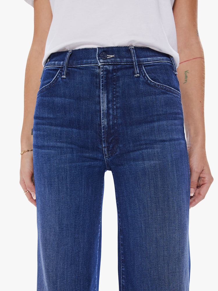Close up view of a woman wide leg jeans with a high rise, 32-inch inseam and a clean hem in a dark blue wash.