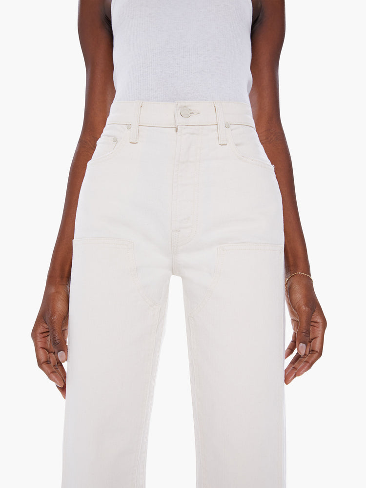 Close waist view of woman High-waisted pants with a wide straight leg, zip fly, oversized patches at the knees and clean ankle-length inseam in a creamy white hue.