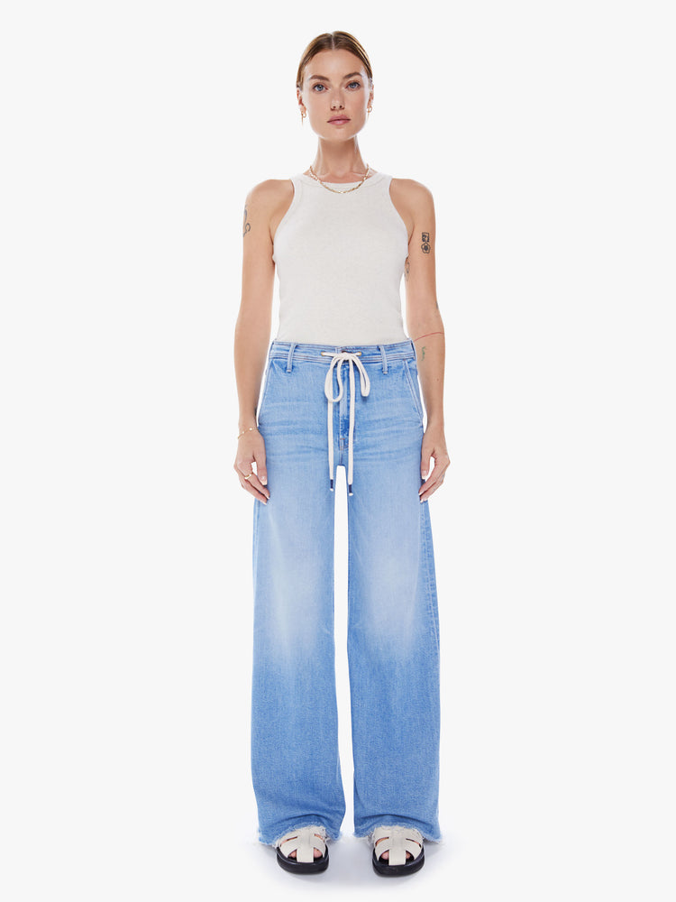 Front view of woman's wide-leg jeans with a high rise, drawstring waistband and a long 34-inch inseam with a frayed hem in a light blue wash and fading at knees.