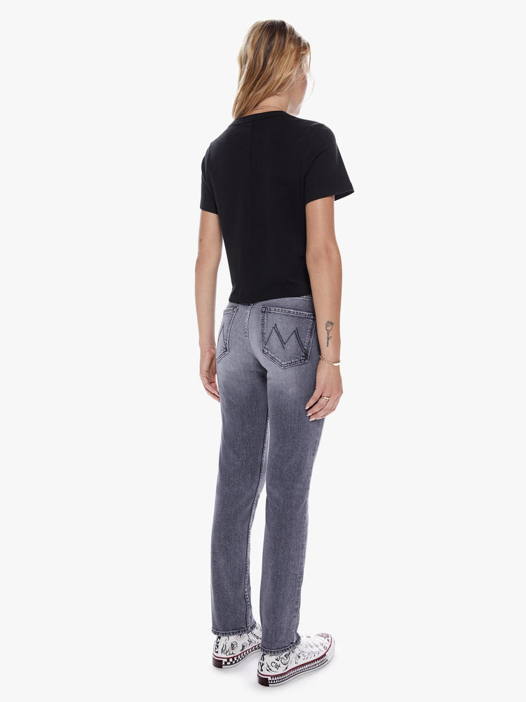 Back full body view of a woman in a midrise straight leg jean with an ankle length inseam and a clean hem in a faded black wash with distressing and tears for a worn-in look