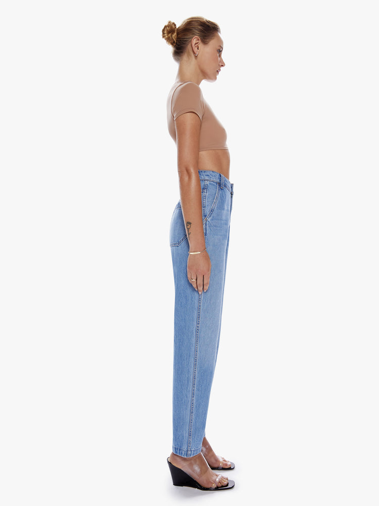 Side full body view of a woman in denim straight leg jean from SNACKS from mothers homage to throwback styles of the 80s and 90s, the high rise ankle jeans features a slightly v-shaped waistband, hammer loop, and a loose fit in a faded mid blue wash