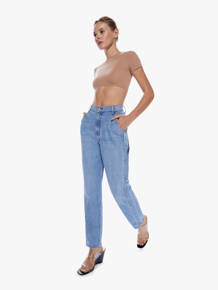 In motion walk full body view of a woman in denim straight leg jean from SNACKS from mothers homage to throwback styles of the 80s and 90s, the high rise ankle jeans features a slightly v-shaped waistband, hammer loop, and a loose fit in a faded mid blue wash