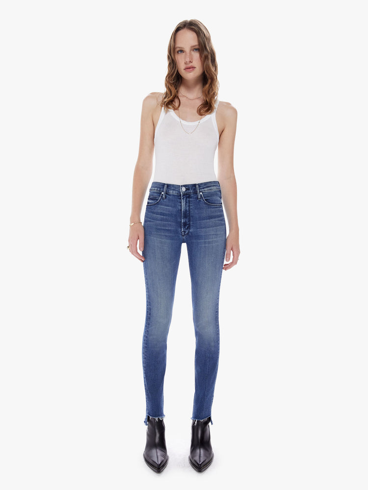 Front view of a woman in our most popular mid rise jean with a straight leg and an ankle length inseam and a frayed step hem made from denim with a touch of stretch in a dark blue wash with subtle fading and whiskering