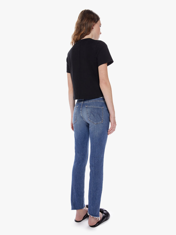 Back view of a womens medium blue wash jean featuring a mid rise, straight leg, and an ankle length crop step hem.