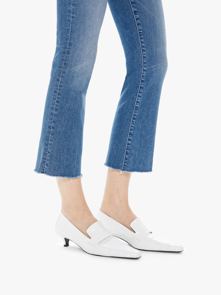 Hem detail view of women's medium blue high rise flare with framed hem and ankle length inseam