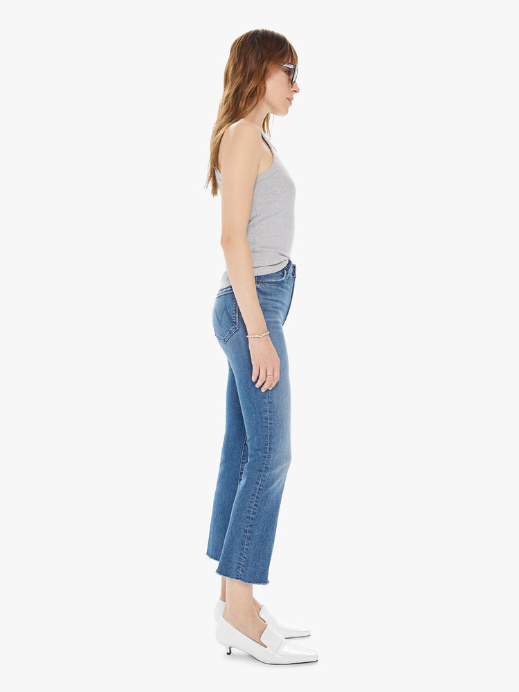 Side view of women's medium blue high rise flare with framed hem and ankle length inseam