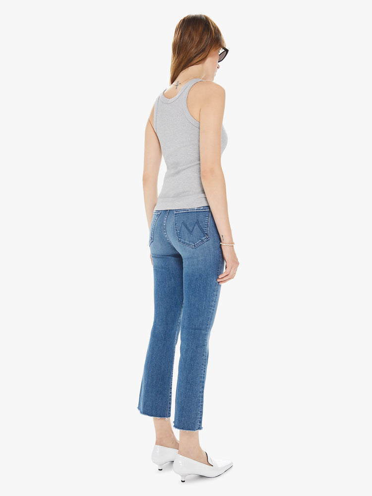 Back view of women's medium blue high rise flare with framed hem and ankle length inseam