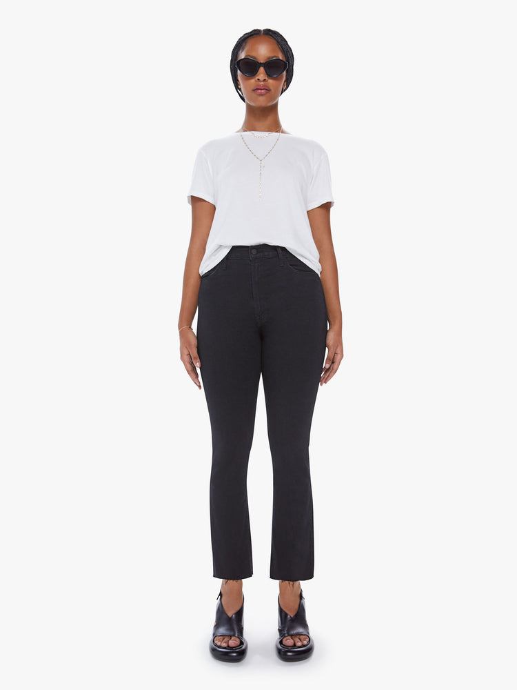 Front view of a womens black jean featuring a high rise, flare leg, and a raw cut ankle length hem.