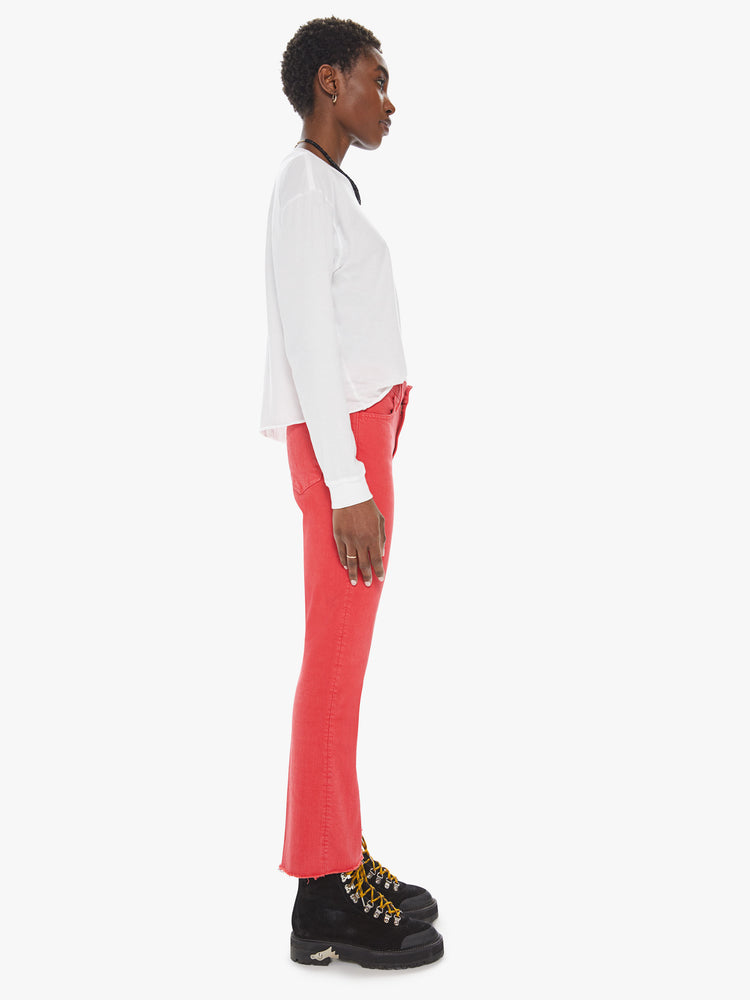 Side view of a womens red flare leg jean featuring a raw cut hem.