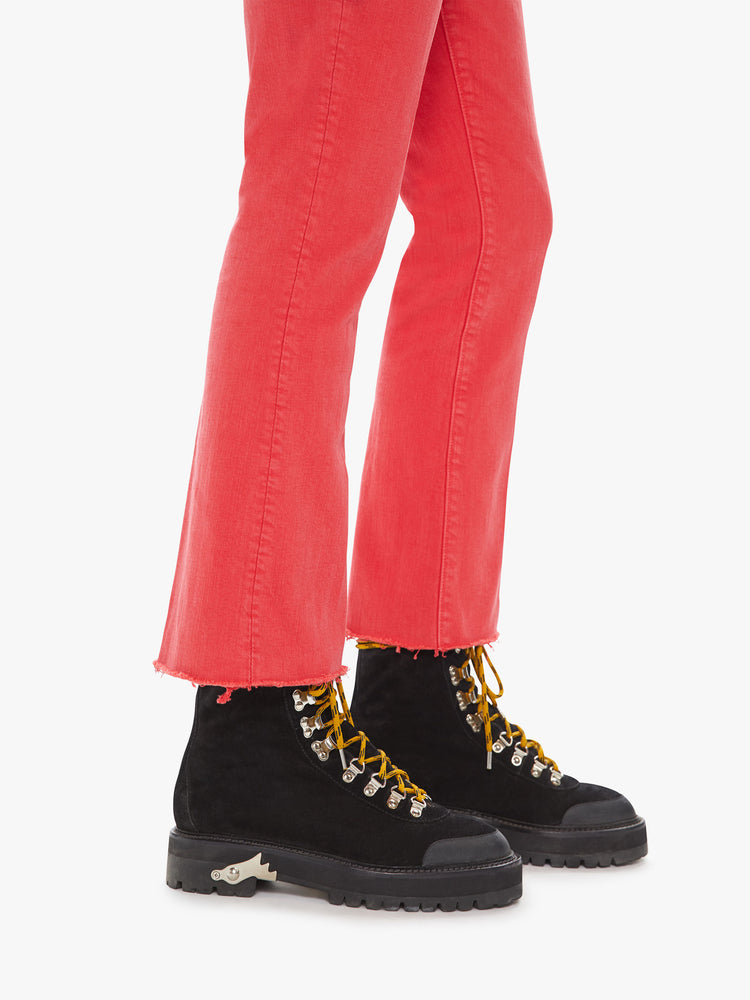 Side close up view of a womens red flare leg jean featuring a raw cut hem.