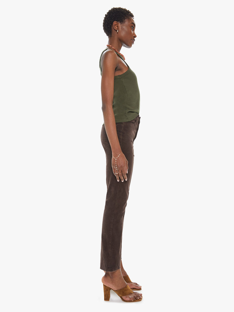 Side view of a womens brown corduroy pant featuring a high rise and a raw cut flare hem.