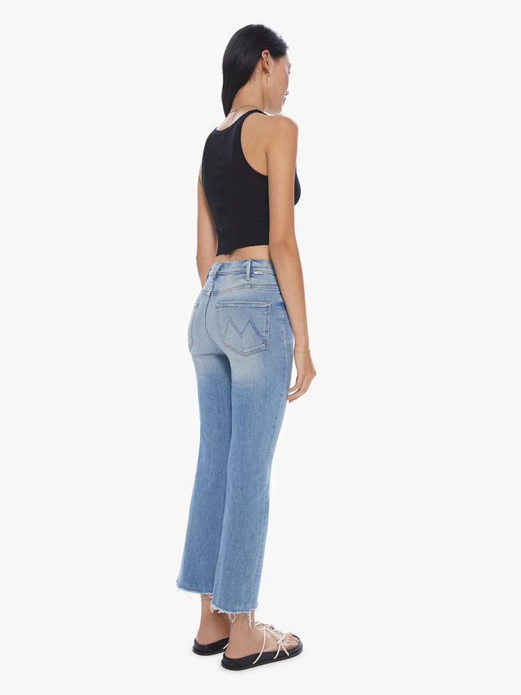 Back view of a womens high rise jean in a light blue wash, featuring a flare leg with a raw hem.