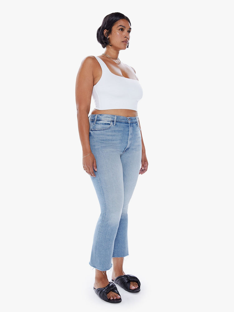 Front 3/4 view of a womens high rise jean in a light blue wash, featuring a flare leg with a raw hem.
