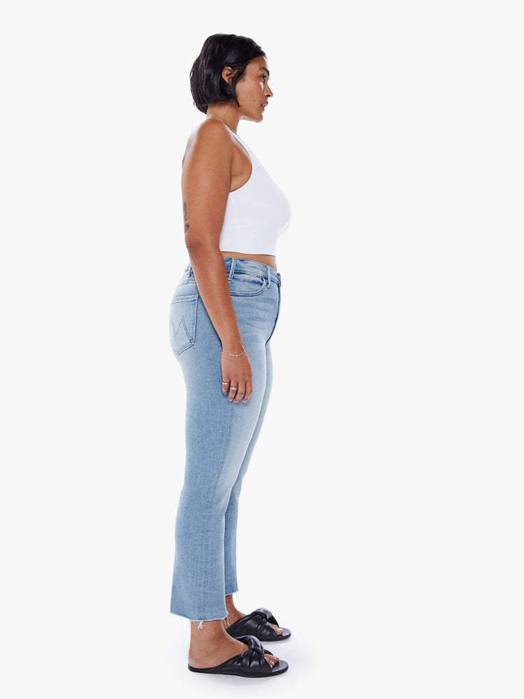Side view of a womens high rise jean in a light blue wash, featuring a flare leg with a raw hem.