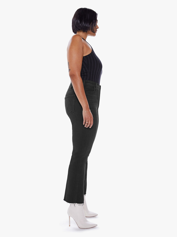 Side view of a womens black wash jean featuring a high rise, flare leg, and frayed hem.